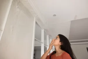 Shocked homeowner woman inspecting home with paint peeling and coating failure